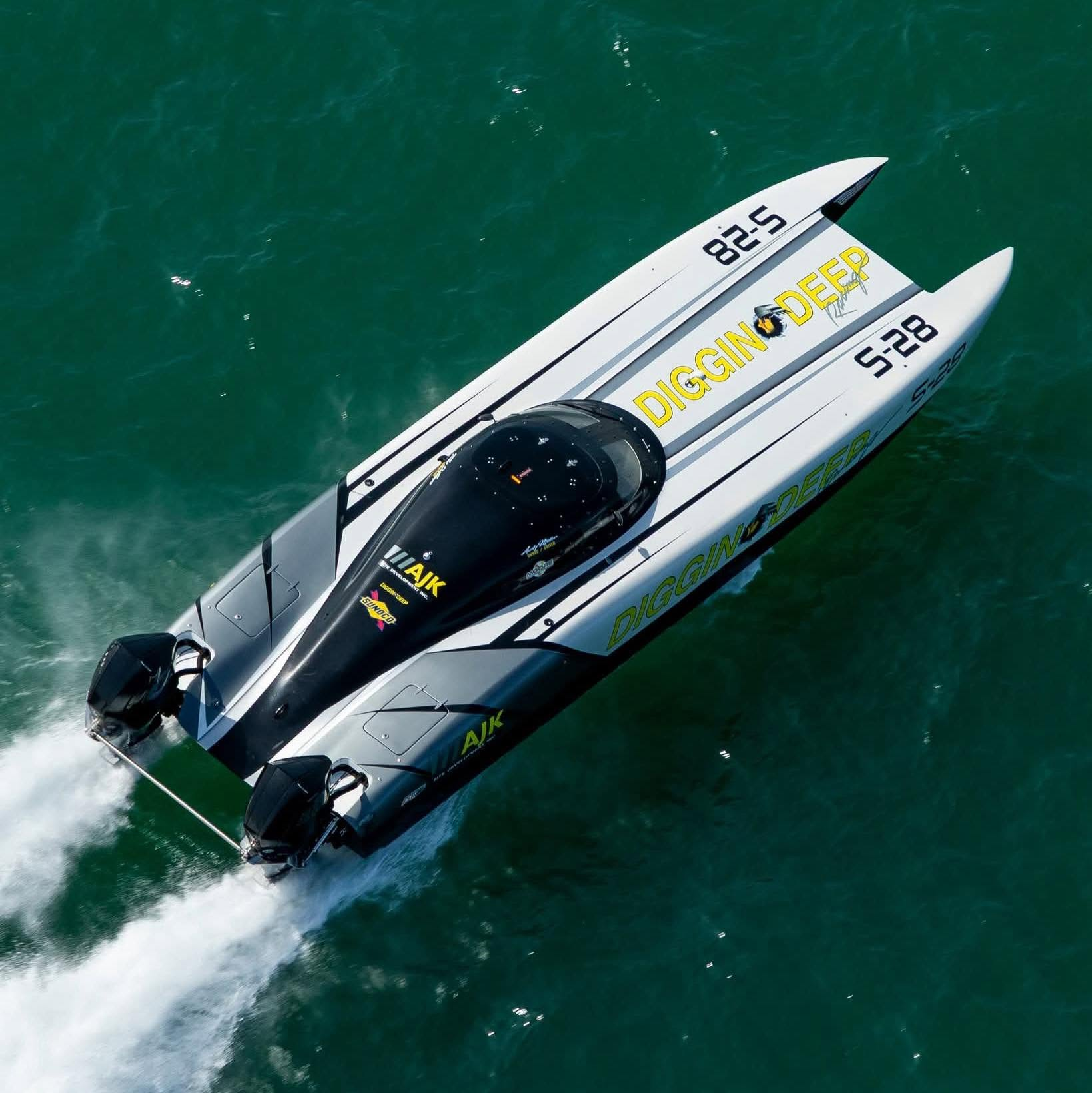 Aerial view of Diggin Deep S-28 running across green water, with its twin hulls and outboards visible.